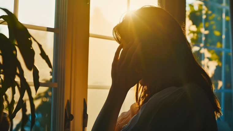 5 Reasons Why Depression Screening Is Now Recommended for All Adults A woman's silhouette standing in front of a window with her hand to her head | 5 Reasons Why Depression Screening Is Now Recommended for All Adults | Mindful Health Solutions