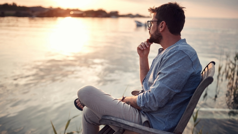 Embrace-These-7-Types-of-Rest Man sitting in chair on a doc enjoying the sunset | Embrace These 7 Types of Rest | Mindful Health Solutions