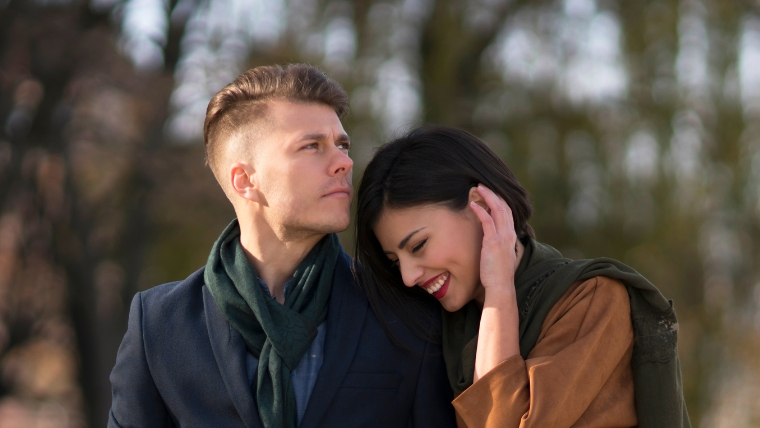 The-4-Attachment-Styles-Which-are-you A couple walking outside and the man is looking away with a serious face while the woman is smiling and leaning into him | The 4 Attachment Styles Which are you? | Mindful Health Solutions