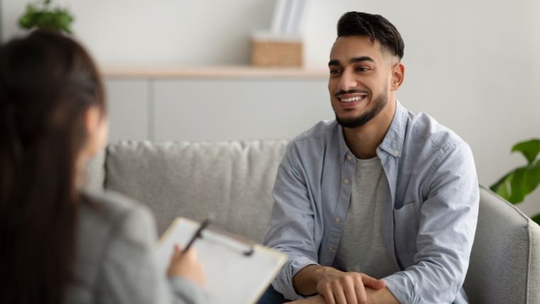 Therapy-Enhancement-10-Topics-to-Kickstart-Meaningful-Discussions Man on couch in therapist office smiling at his therapist | Therapy Enhancement :10 Topics to Kickstart Meaningful Discussions | Mindful Health Solutions