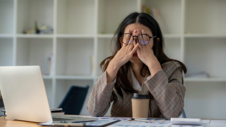 8-Unexpected-Reasons-Why-Perfectionism-Is-Bad-for-Your-Mental-Health 8 Unexpected Reasons Female person at desk with hands on face, looking stressed, overwhelmed, and burnt out | Why Perfectionism Is Bad for Your Mental Health | Mindful Health Solutions