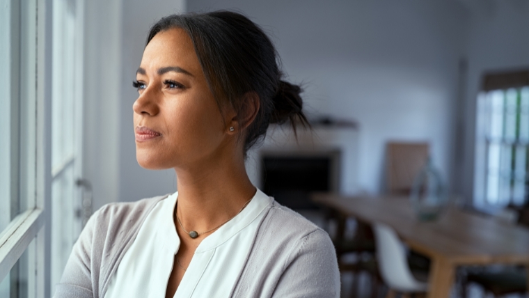 Are-You-Skeptical-About-TMS-Discover-What-the-Science-Is-Saying Thoughtful woman of color looking outside window | Are You Skeptical About TMS Discover What the Science Is Saying | Mindful Health Solutions