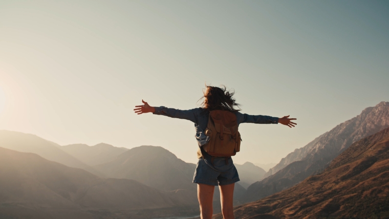 Reimagine-OCD-Treatment-with-TMS-A-Breakthrough-You-Should-Know-About Female person standing on top of mountain and looking out at the view with hands raised victoriously | Reimagine OCD Treatment with TMS A Breakthrough You Should Know About | Mindful Health Solutions