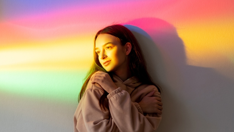 9-Coping-Strategies-to-Navigate-New-Years-with-Depression Young woman standing in rainbow light | 9 Coping Strategies to Navigate New Year's with Depression | Mindful Health Solutions