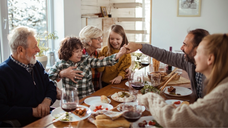 Holiday-Traditions-and-Mental-Health-Discover-the-Positive-Impact A family sitting and laughing around a table at the holidays | Holiday Traditions and Mental Health Discover the Positive Impact | Mindful Health Solutions