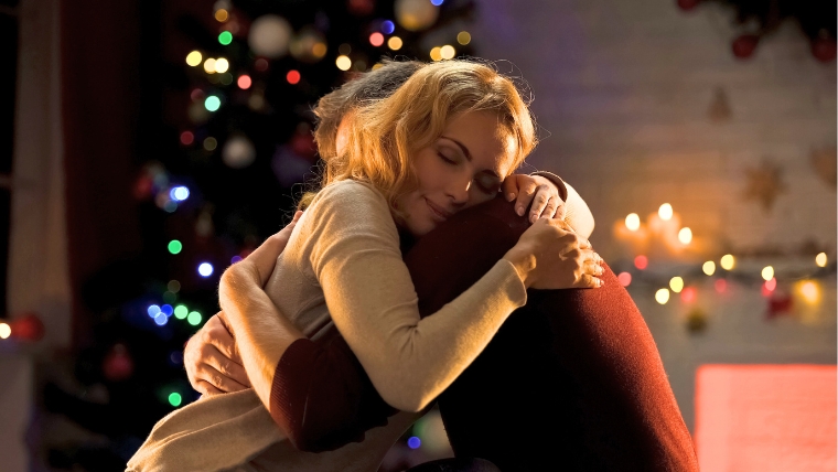 How-To-Support-Loved-Ones-with-Mental-Health-Challenges-During-the-Holidays A man and woman hugging in front of a Christmas tree | How To Support Loved Ones with Mental Health Challenges During the Holidays | Mindful Health Solutions