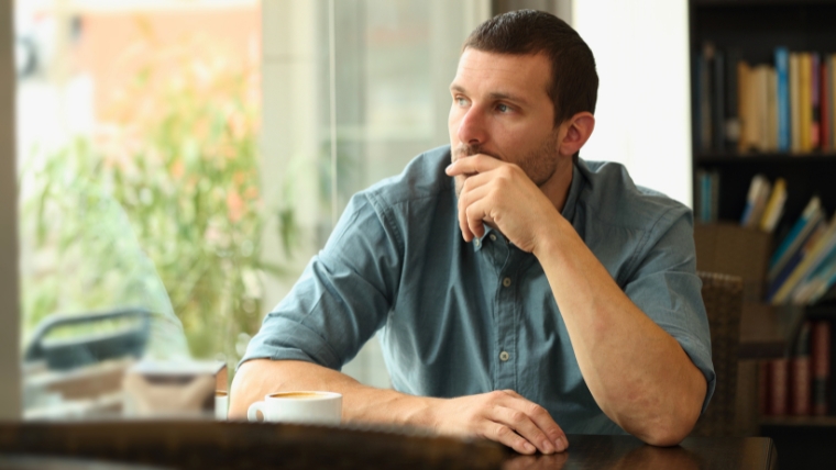 TMS-vs.-Traditional-Antidepressants-Which-Works-Best-for-You Man sitting in coffee shop looking out the window | TMS vs. Traditional Antidepressants Which Works Best for You | Mindful Health Solutions