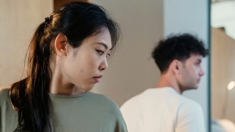 How-Depression-Impacts-Your-Relationships-and-16-Effective-Coping-Strategies A woman looking over her shoulder at her male partner, both avoiding eye contact and looking sad and serious | How Depression Impacts Your Relationships and 16 Effective Coping Strategies | Mindful Health Solutions