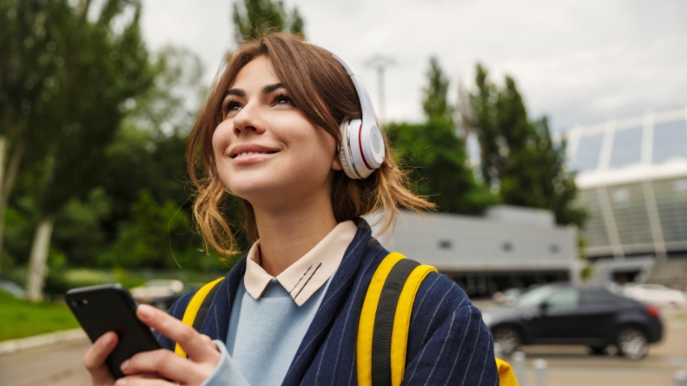 7 Ways Music and Podcasts Effectively Soothe Anxiety Professional woman with headphones on who is tilting her head up toward the sky with a smile on her face | 7 Ways Music and Podcasts Effectively Soothe Anxiety | Mindful Health Solutions