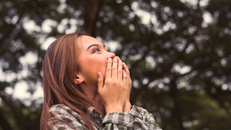 How To Break Free from Negative Self-Talk and Improve Your Mental Health Woman standing outside with her hands over her mouth, looking happy and relieved | How To Break Free from Negative Self-Talk and Improve Your Mental Health | Mindful Health Solutions