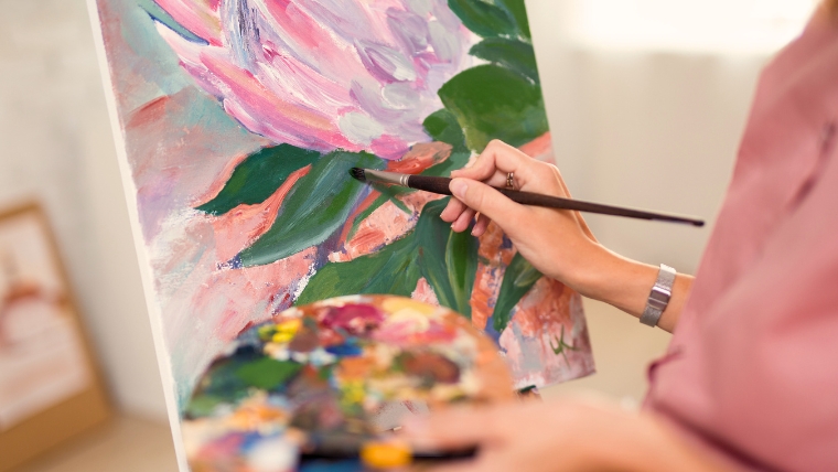 9 Amazing Therapeutic Benefits of Art for Anxiety Management A woman's hand holding a paint palette and painting a flower on a canvas | 9 Amazing Therapeutic Benefits of Art for Anxiety Management | Mindful Health Solutions